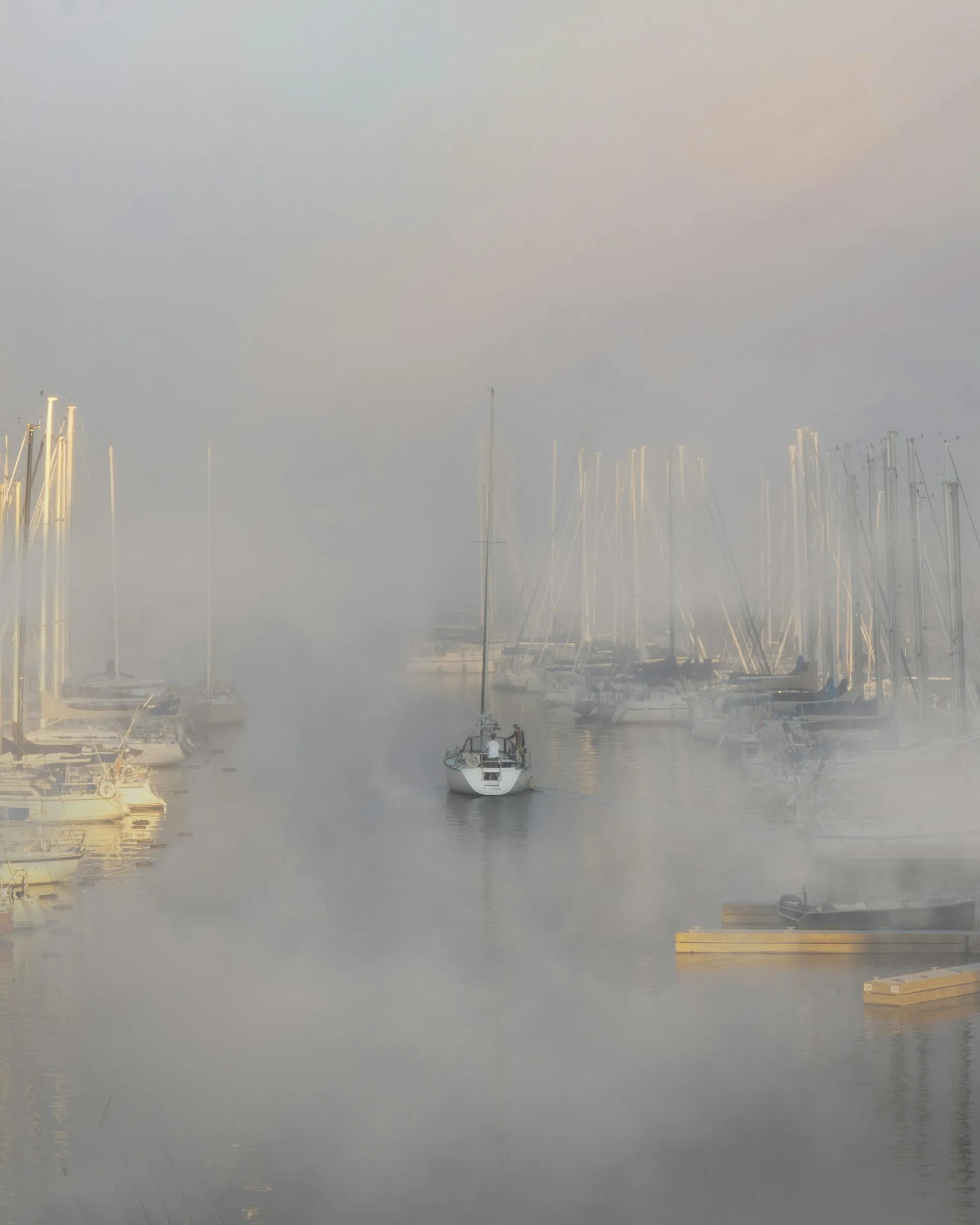 Boat leaving harbor during foggy afternoon.